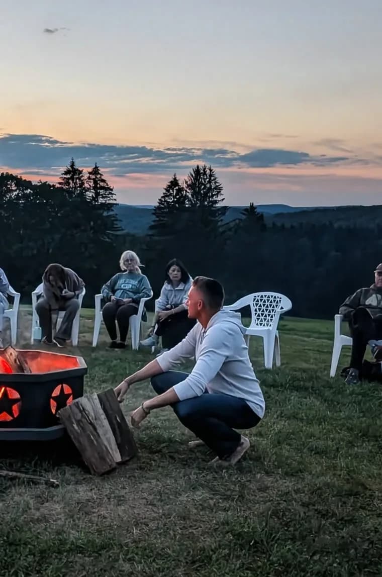 Sean Corey tending a fire circle with retreat guests at sunset